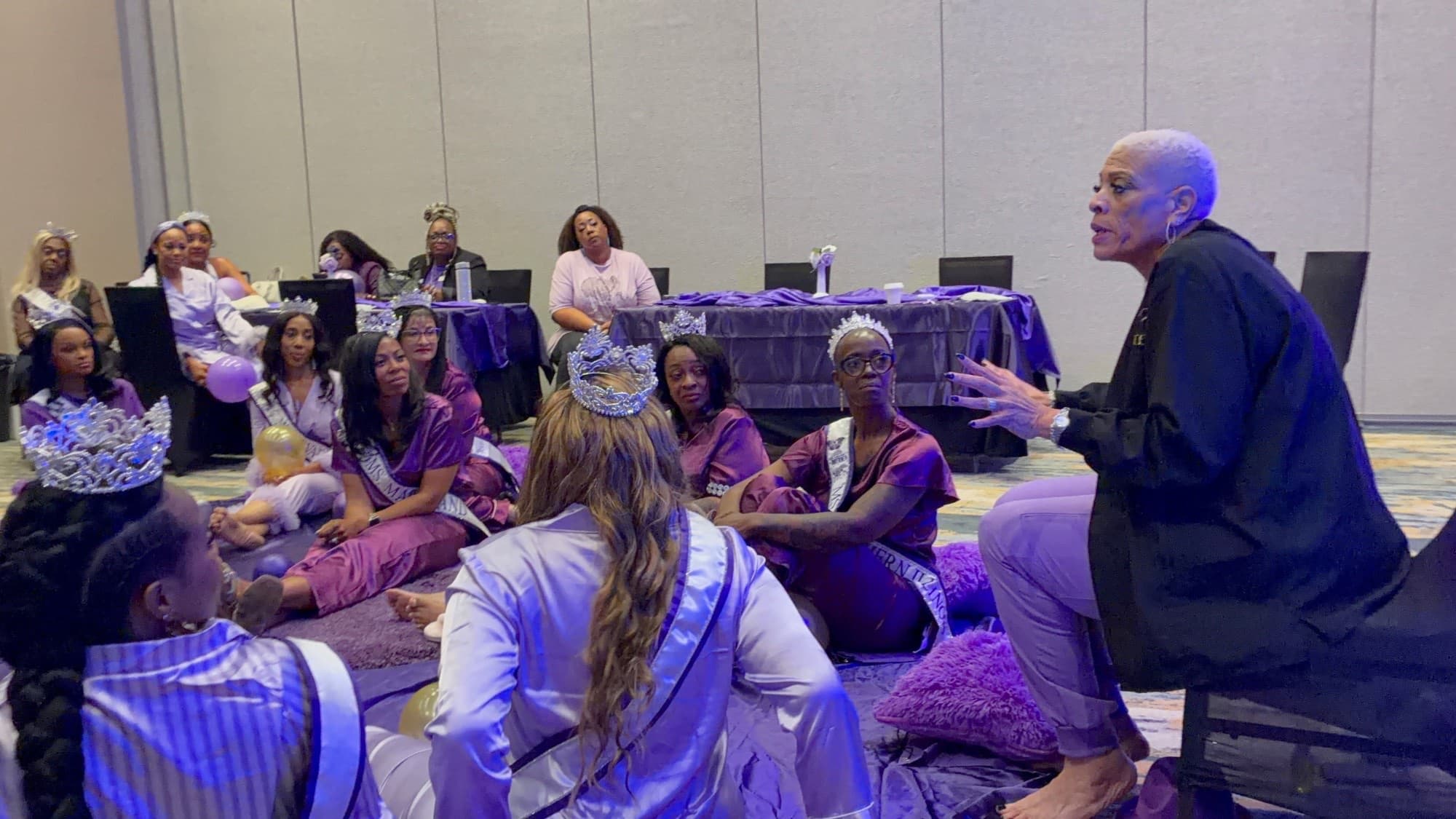 Dr. Sneed coaching a circle of crowned women at a mentoring session