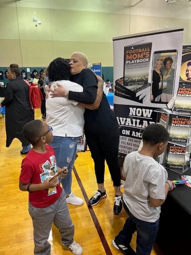 Dr. Sneed hugging a reader at a community book event