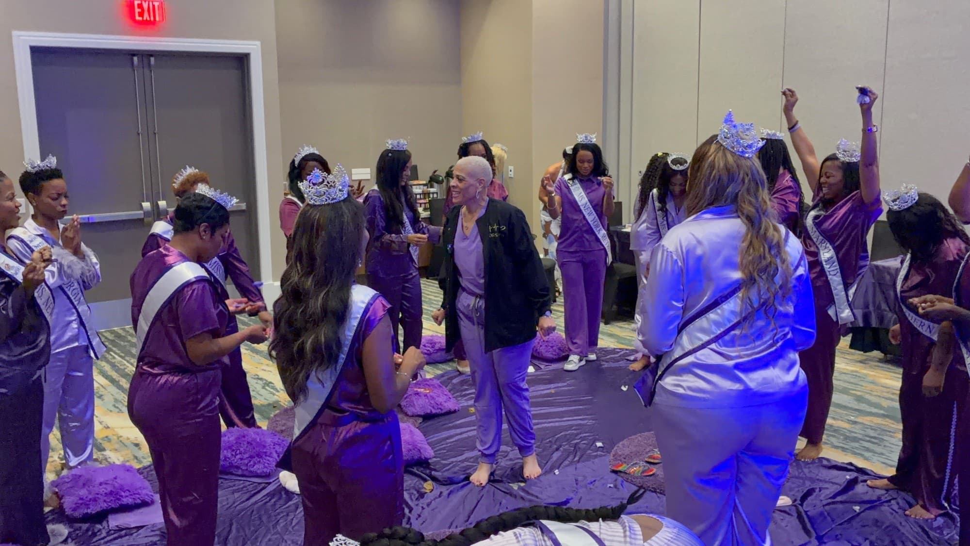 Dr. Sneed with a circle of crowned pageant queens at a women's empowerment event