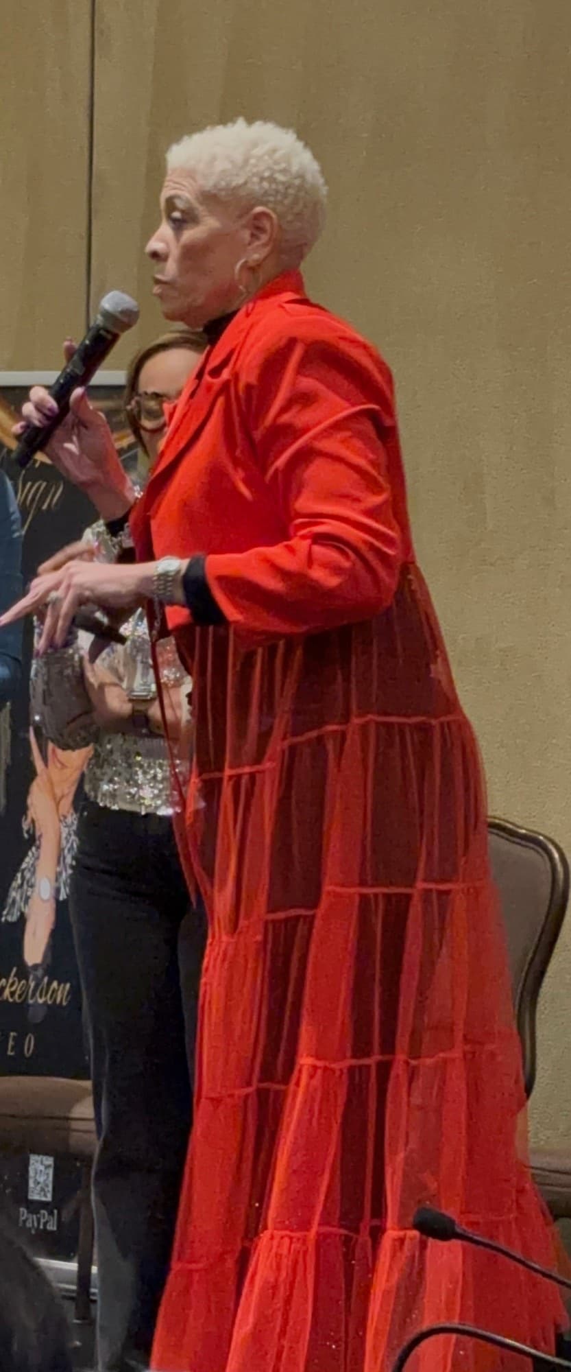 Dr. Sneed speaking with a microphone in a red dress